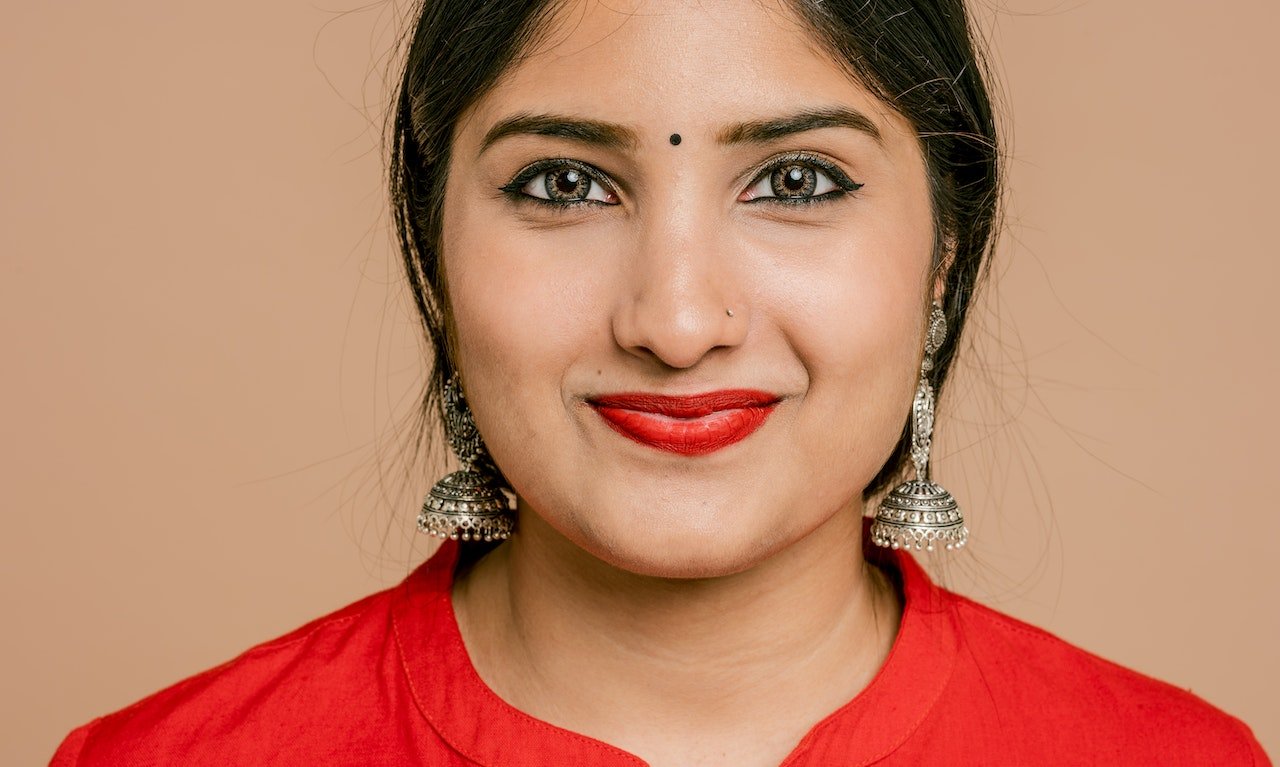 A woman wearing a red blouse and red lipstick and smiling. Unlocking the Power of Self-Love: Your Essential Skincare Routine